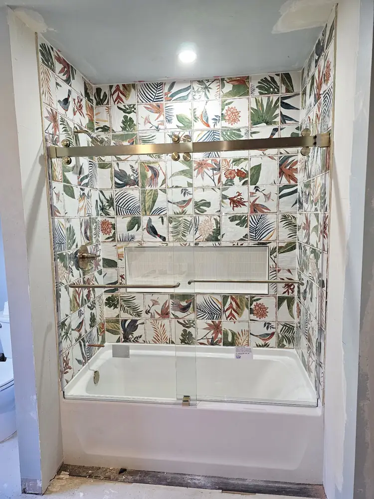 Finished tub surround with gold fixtures and a sliding glass door