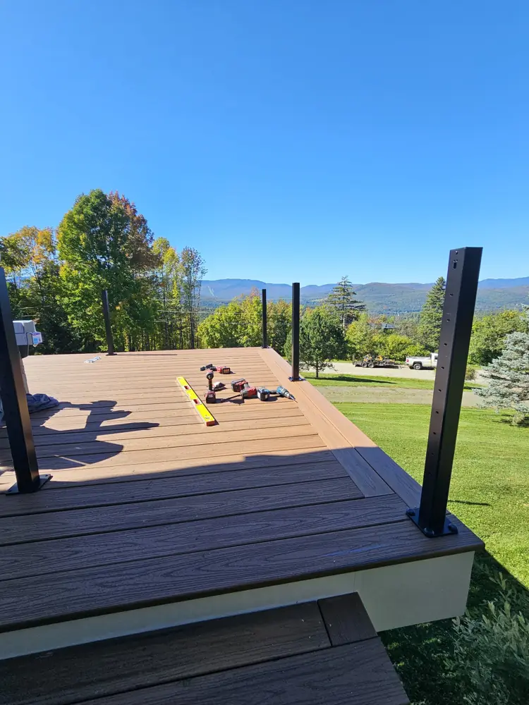 New Trex decking with black aluminum rail posts going in, mountains behind