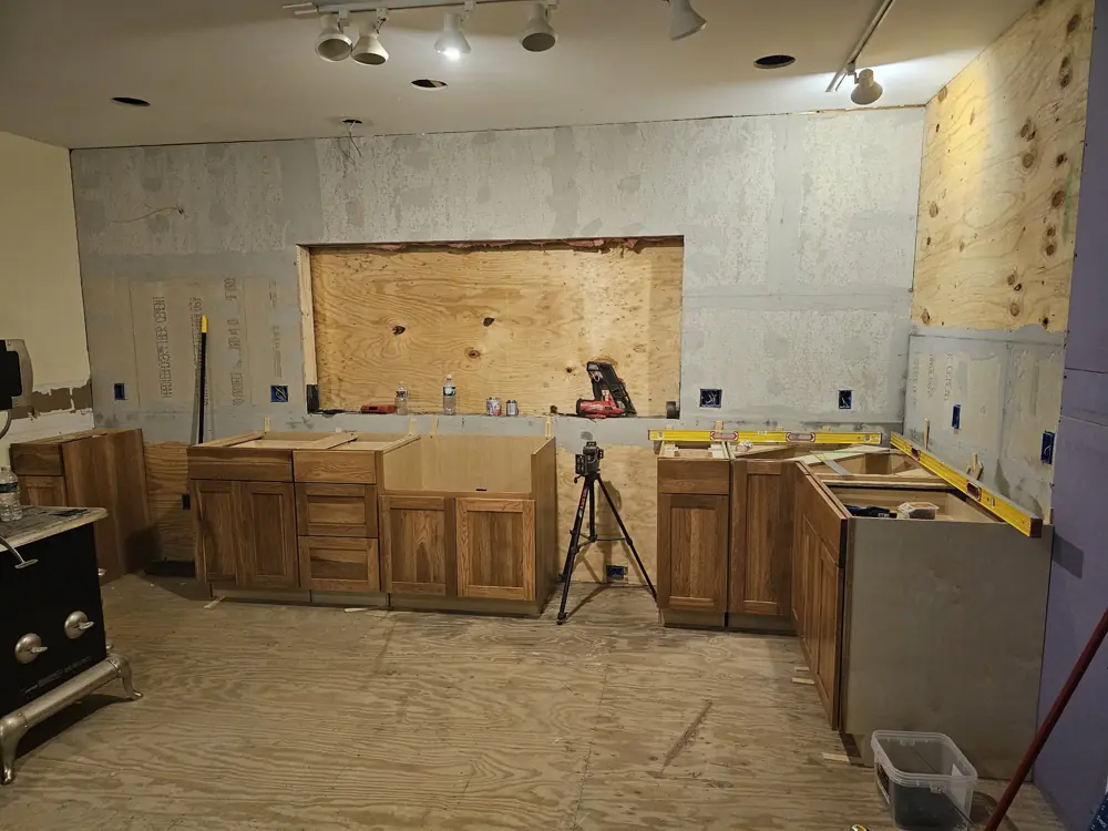 New cabinets being set and leveled against cement board walls