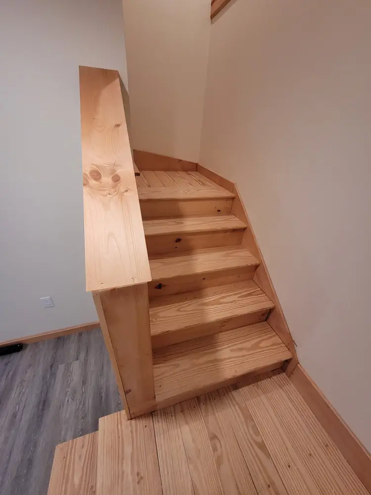 Finished pine stairs seen from above with wide pine cap on the half wall